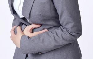 胃痛でお腹を押えるOL